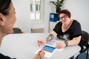 Fachfrau Andrea Bally erklärt einer Kundin die Unterlagen für die externe Lohnbuchhaltung
