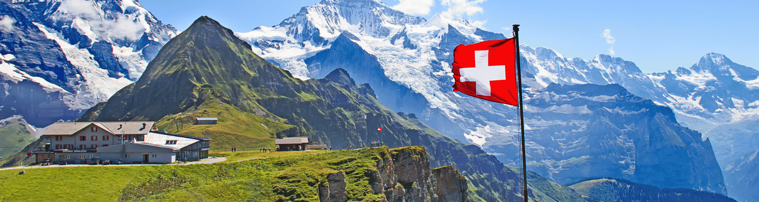 Schweizer Flagge vor Alpenpanorama – Beitrag über Nachhaltigkeit und Steuern in der Schweiz für Unternehmen.